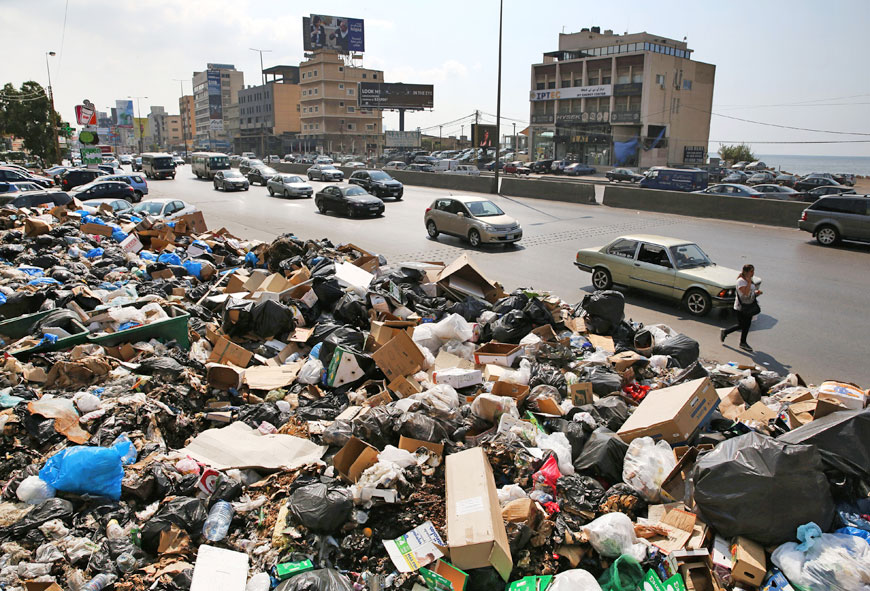 Lebanese citizens pass a pile of garbage blocking a street in the town of Jal El Dib, east Beirut, Lebanon, Wednesday (AP photo)