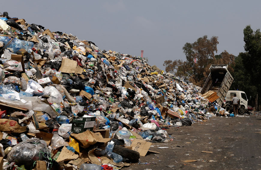 A dump truck adds trash to a pile of garbage on the bank of the Beirut River, in Beirut, Lebanon, Monday (AP photo)
