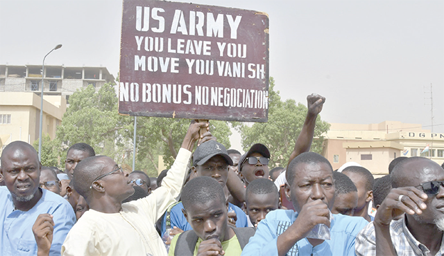 Protesters react as a man holds up a sign demanding that soldiers from the United States army leave Niger without negotiation during a demonstration in Niamey, on April 13 (AFP photo)