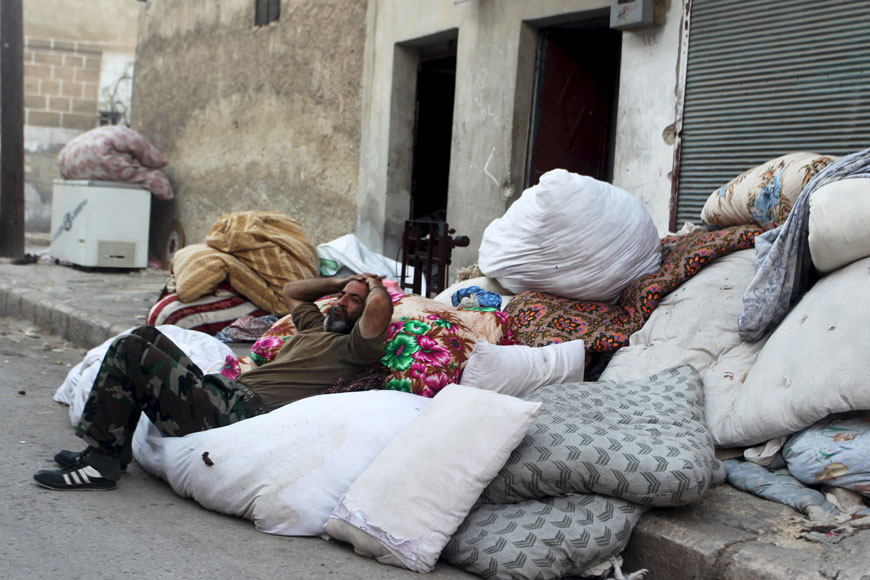 A man rests on pillows and cushions to be transported to another place in Tariq Al Bab neighbourhood of Aleppo, Syria, Sunday (Reuters photo)
