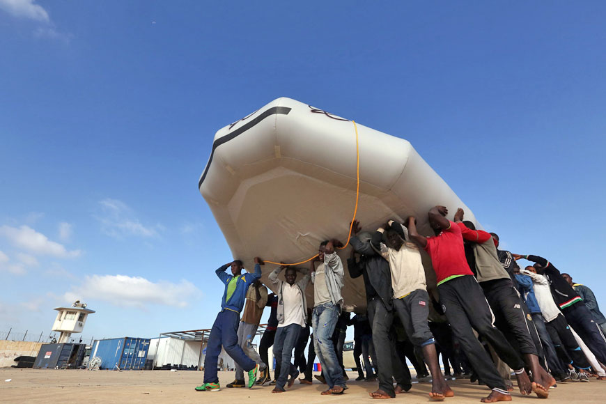 Migrants carry a raft, after being rescued by the Libyan coastguard, at a naval base near the capital Tripoli on Monday (AFP photo)