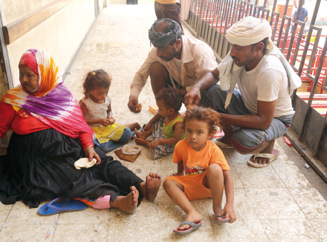 Members of displaced Yemeni families who fled battles between government forces and Houthi fighters near the Hodeida airport share a meal on the balcony of a school used as temporary housing inside the city of Hudeida on Sunday (AFP photo)