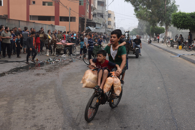 Youngsters carry bags of bread as they ride a bicycle in Rafah in the southern Gaza Strip on Saturday (AFP photo)