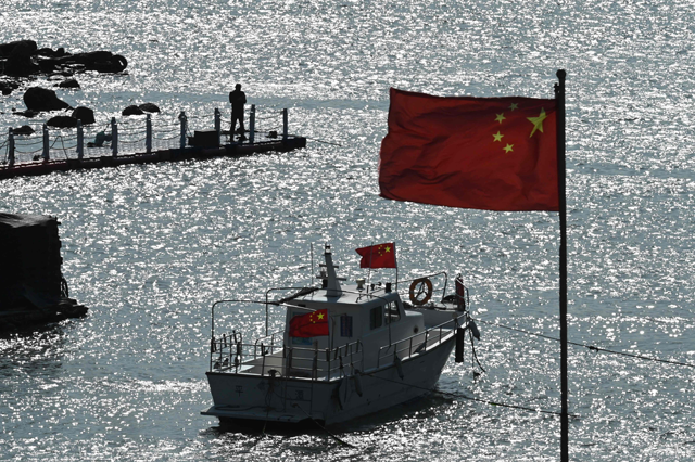 A man stands on a jetty behind a tourist boat and Chinese flags on Pingtan island, opposite Taiwan, in China's southeast Fujian province on Sunday (AFP photo)
