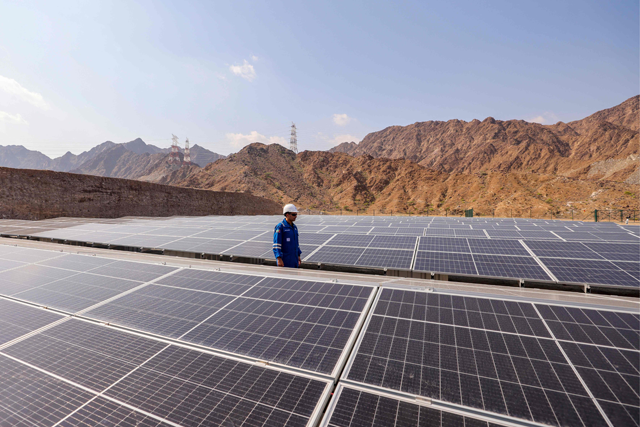 An engineer walks past solar panels at the ADNOC Facility in Fujairah on Tuesday. Using novel technology developed by Omani start-up 44.01, the solar-powered plant will suck carbon dioxide from the air, dissolve it in seawater and inject it deep underground, where it will mineralise over a period of months (AFP photo)