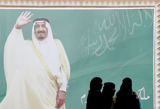 Women walk past a poster of Saudi Arabia's King Salman Bin Abdulaziz Al Saud during Janadriyah Cultural Festival on the outskirts of Riyadh, Saudi Arabia, on February 12 (Reuters file photo)