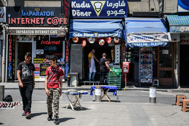 Syrian men pass by a Syrian fast-food restaurant on Monday in Fatih neighbourhood in Istanbul. Receptionist, waiter, hairdresser, pastry seller : these are the jobs of the young Syrians who abandoned their dreams in Damascus to start from scratch in Istanbul (AFP photo)
