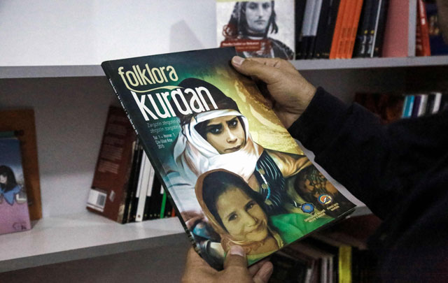 A Kurdish man carries a book on Kurdish folklore at a library in Kurdish-majority Qamishli in northeast Syria on January 11 (AFP photo)