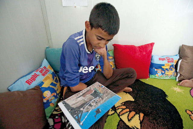 An Iraqi boy who lost his arm during Mosul war looks at a photographic rendition by US photographer Brian McCarty at Debaga camp for the displaced on the outskirts of Irbil, Iraq July 8 (Reuters photo)