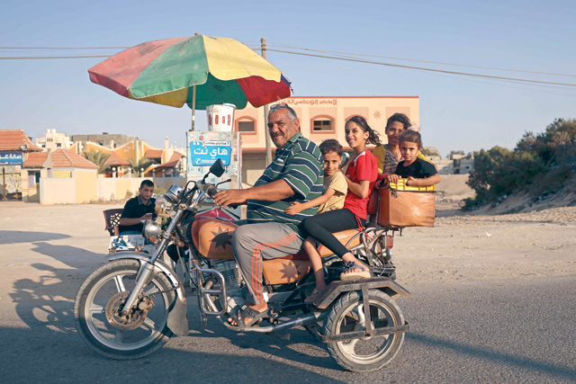 A Palestinian man smiles as he rides a motorcycle with his children in Rafah in the southern Gaza Strip on Thursday (AFP photo)