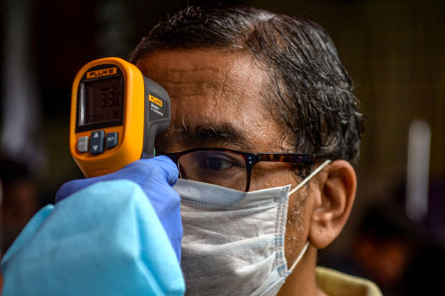 A health worker checks the body temperature of a resident during a COVID-19 coronavirus screening in Mumbai on Wednesday (AFP photo)