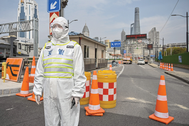 A transit officer, wearing a protective gear, controls access to a tunnel in the direction of Pudong district in lockdown as a measure against the Covid-19 coronavirus, in Shanghai, on Monday (AFP photo)