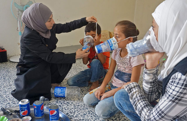 Um Majid (left) tries an improvised gas mask on family members in her home in Binnish in Syria’s rebel-held northern Idlib province as part of preparations for any upcoming raids on Wednesday (AFP photo)