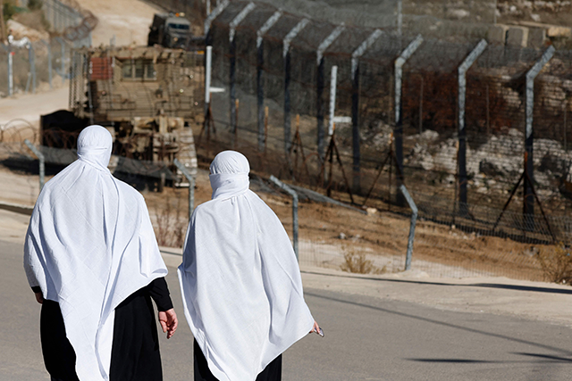 Druze women walk near the fence leading into the UN-patrolled buffer zone, which separates Israeli and Syrian forces on the Golan Heights, near the Druze village of Majdal Shams in the Israel-annexed Golan Heights on December 15, 2024 (AFP photo)
