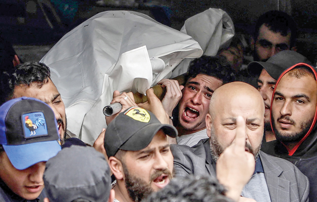 Mourners carry the body of one of the people who died when their boat capsized a day earlier off the coast of Tripoli, at the morgue of a hospital of the northern Lebanese city, on Sunday (AFP photo)