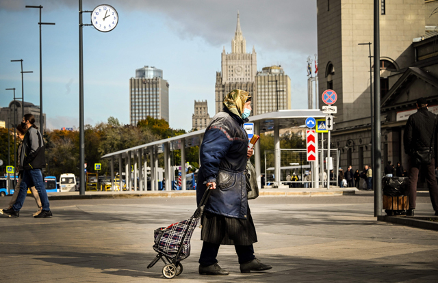 A woman wearing a face mask and carrying candles walk through central Moscow on Tuesday (AFP photo)