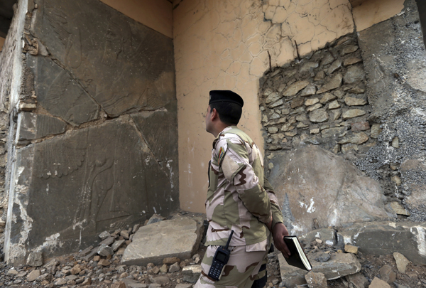 An Iraqi army officer looks at a damaged carved stone slab, which was destroyed by the Daesh terror group militants, at the entrance of the ancient site of Nimrud, some 30km southeast of Mosul, Iraq, on Wednesday (AP photo)
