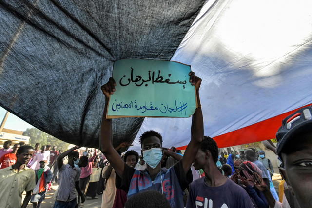 A Sudanese anti-coup protester carries a placard which reads in Arabic 'Down with [General Abdel Fattah] Al Burhan' during a demonstration in the 'Street 40' of the capital's twin city of Omdurman on Thursday (AFP photo)