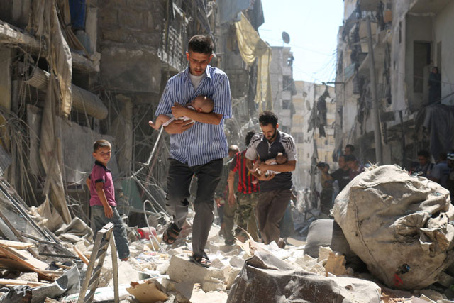 Syrian men carrying babies make their way through the rubble of destroyed buildings following a reported air strike on the rebel-held Salihin neighbourhood of the northern city of Aleppo, on September 11 (AFP photo)