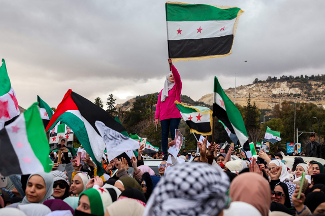 People wave independence-era Syrian flags during a demonstration celebrating the fall of Syrian president Bashar Al Assad at Ummayad Square in the capital Damascus on December 27, 2024 (AFP photo)