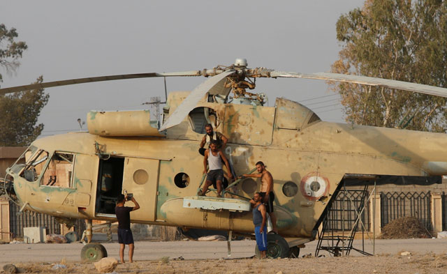 People take a picture on a damaged helicopter in Deir Ezzor Airport, Syria, on Wednesday (Reuters photo)