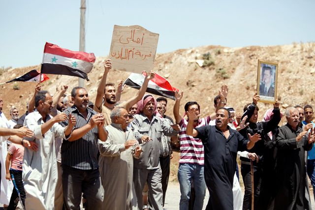 People chant slogans as they hold Syrian flags in Umm Al Mayazen, in the countryside of Daraa, Syria, on Tuesday (Reuters photo)