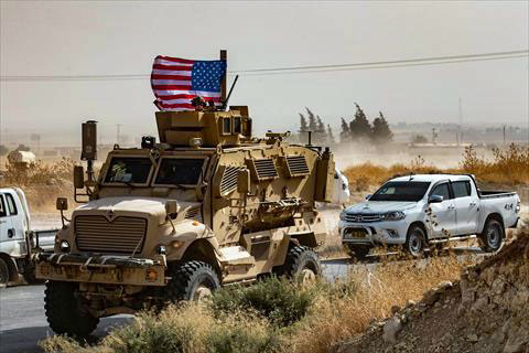 A US soldier sits atop an armoured vehicle during a demonstration by Syrian Kurds against Turkish threats next to a base for the US-led international coalition on the outskirts of Ras  Al Ain town in Syria's Hasakeh province near the Turkish border on Sunday (AFP photo)
