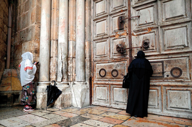 Two Christian women pray by the closed door of the main entrance of the Church of the Holy Sepulchre in the Old City of Jerusalem on Monday, after Christian leaders took the rare step of closing the church, seen as the holiest site in Christianity, the previous day at noon (AFP photo)