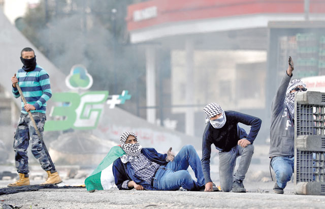 Palestinian demonstrators take cover during confrontations with Israeli troops near the Jewish settlement of Beit El, in the occupied West Bank on Friday (Reuters photo)