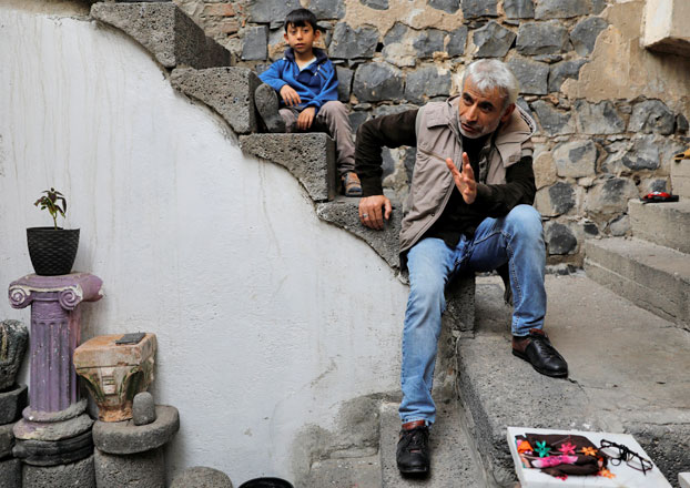 Sukru Gunduz, a Sur resident whose house was demolished, and his son sit on the stairs of their rented home in Sur, a historical district of the southeastern city of Diyarbakir, Turkey, on March 20 (Reuters photo)