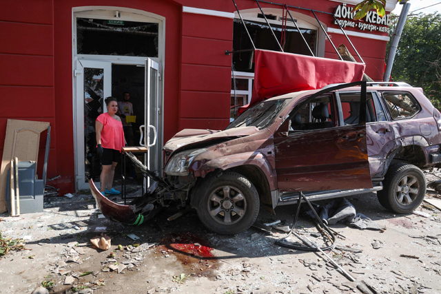A local resident stands next to a damaged car at the site of a missile strike in Chernihiv  on Saturday (AFP photo)