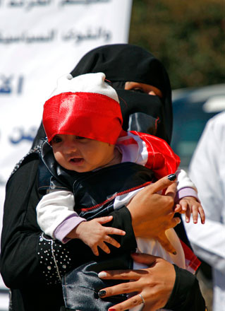 A Yemeni woman carrying a child attends a sit-in on Tuesday outside the United Nations offices in the capital Sanaa, demanding an end to a war that has left millions displaced and at risk of famine (AFP photo)