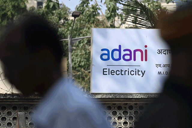 A pedestrian walks past Adani electricity office in Mumbai on Tuesday (AFP photo)