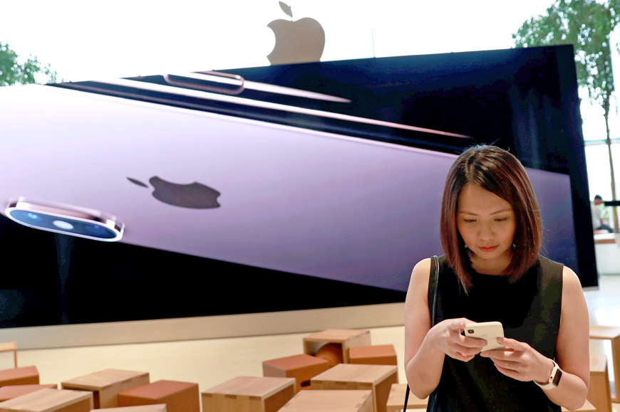 A woman checks her phone at a flagship Apple store at Iconsiam shopping mall in Bankok, Thailand, on November 9  (Reuters photo)