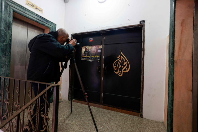 A man photographs the closed door of the Doha-based Al Jazeera TV channel in the occupied-West Bank city of Ramallah on Thursday (AFP photo)