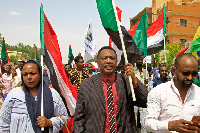 Sudanese protesters lift national flags during an anti-coup demonstration in the Bashdar station area in southern Khartoum, on Tuesday (AFP photo)