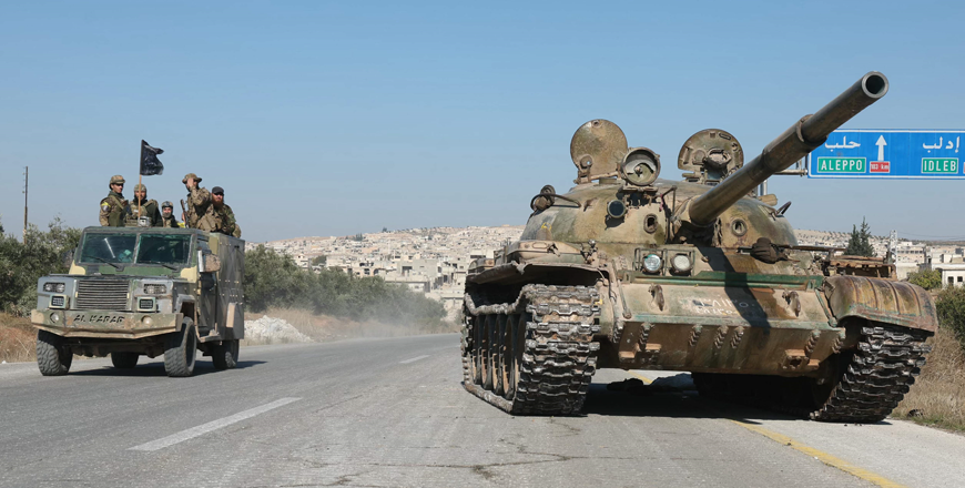 Anti-government fighters drive past a tank, left behind by regime forces, on the road leading to the Syrian town of Khan Sheikhun, in the northwestern Syrian Idlib province, on Sunday (AFP photo)