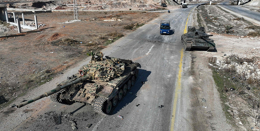 An aerial photo shows a car driving past Syrian army military equipment and vehicles that were abandoned on the highway to Damascus, near the town of Suran north of Syria's Hama city on Tuesday (AFP photo)