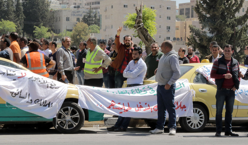 Taxi drivers protest the implementation of ride-hailing apps in front of Parliament on Tuesday (Photo by Osama Aqarbeh)