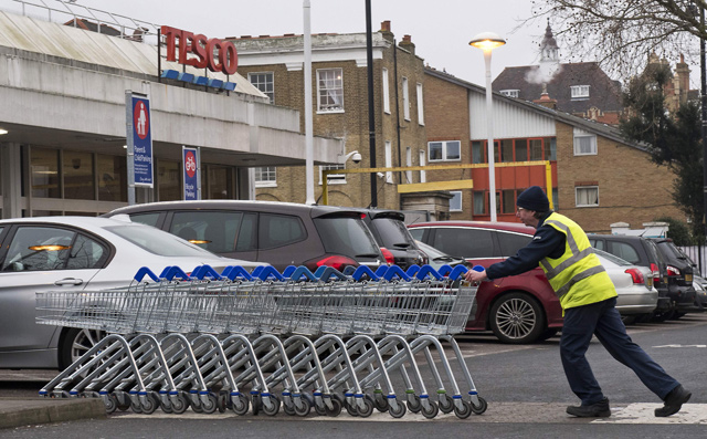In this file photo taken on January 9, 2018, a worker pushes a line of trolleys in the car park at a branch of Tesco in south London  (AFP photo)