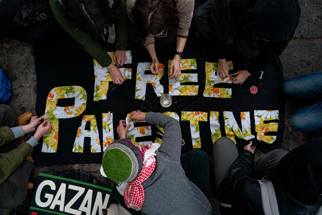 Activists and students sew a banner as they protest near an encampment at University Yard at George Washington University on Saturday in Washington, DC. (AFP photo)