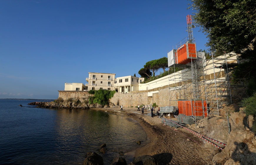 Workers setting up a temporary elevator on the public beach called ‘La Mirandole’ located below a mansion owned by the Saudi royal family in Golfe Juan Vallauris, southeastern France, on Friday (AP photo)