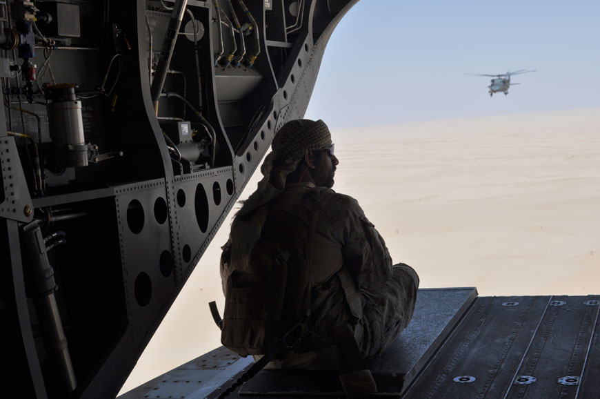 An Emirati soldier stands guard out the rear gate of a Chinook military helicopter, escorted by a Blackhawn helicopter, travelling from Saudi Arabia to Yemen, Monday (AP photo)