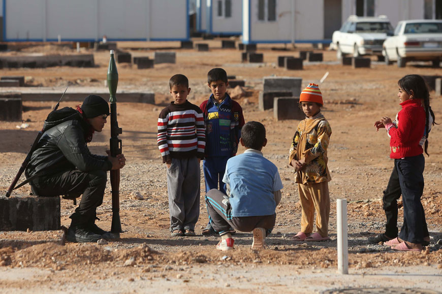 An Iraqi militiaman securing a camp for internally displaced Iraqis from the province of Anbar holds a rocket propelled grenade launcher while sitting near children on Wednesday in Nukhaib, some 200kms West of Karbala (AFP photo)