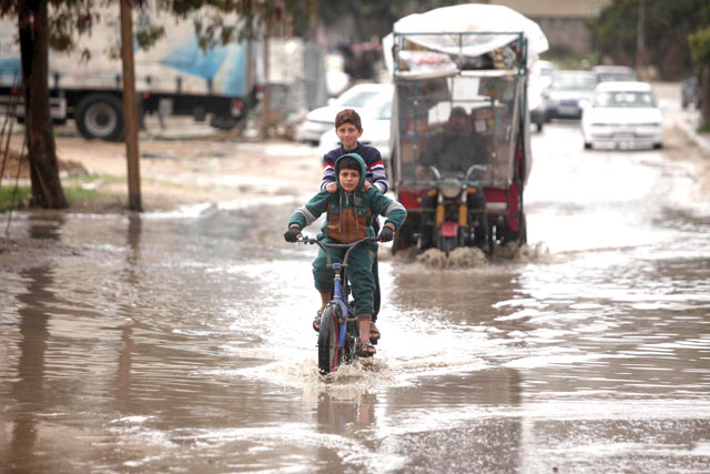 A boy rides a bike on a puddle because of a day-long rainfall in Gaza City, Gaza on Saturday (Anadolu Agency photo)