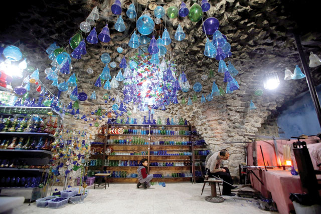 A Palestinian boy looks on as a man works at a glass factory in the old city of Hebron, in the Israeli-occupied West Bank, on January 15 (Reuters photo)