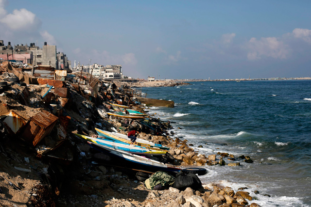   Palestinian fishermen fix their boats and nets on the beach of Gaza City on Thursday (AFP photo)