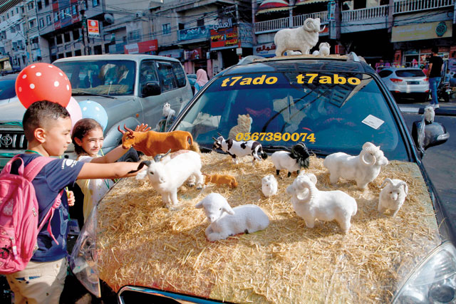 Palestinian children look at a car decorated with sheep and cows in celebration of Eid Al Adha in Gaza City on Thursday (AFP photo) 