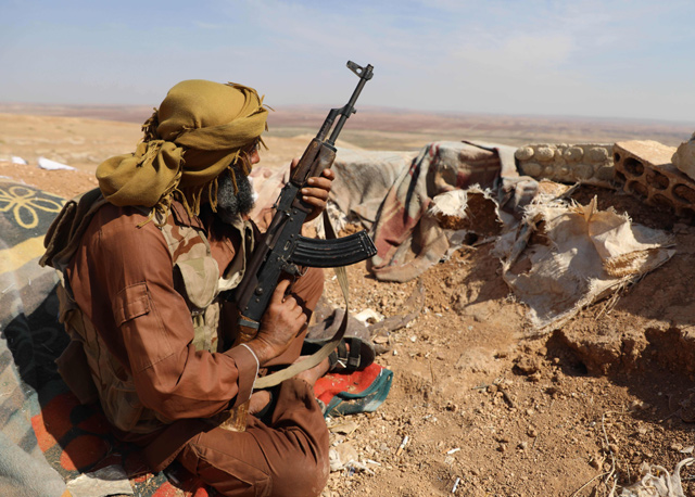 A Syrian rebel-fighter from the National Liberation Front (NLF) takes position in a trench armed with an automatic rifle on a hill in the area of Al Eis in the southwest of Aleppo province, overlooking regime-held territory several kilometres away, on Sunday (AFP photo)
