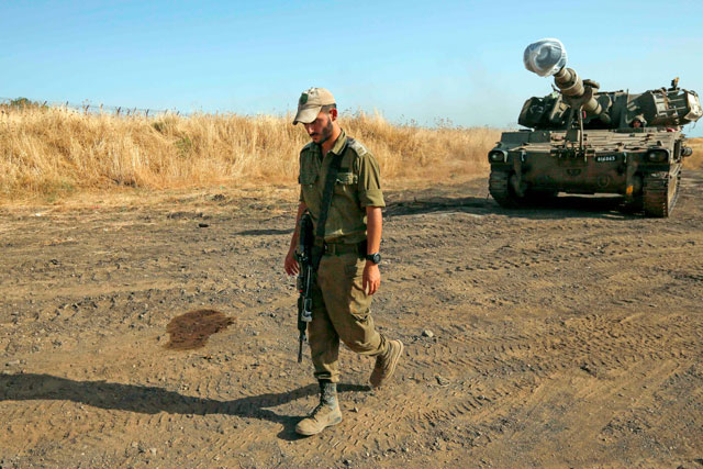   An Israeli soldier walks by a mobile artillery cannon in the Israeli-occupied Golan Heights on Sunday (AFP photo)